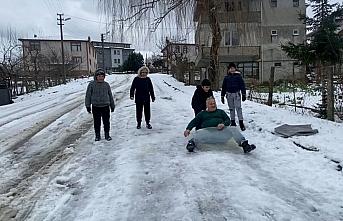 Çocukların kar keyfini bozmayan kepçe operatörü onlarla kayarak eğlendi